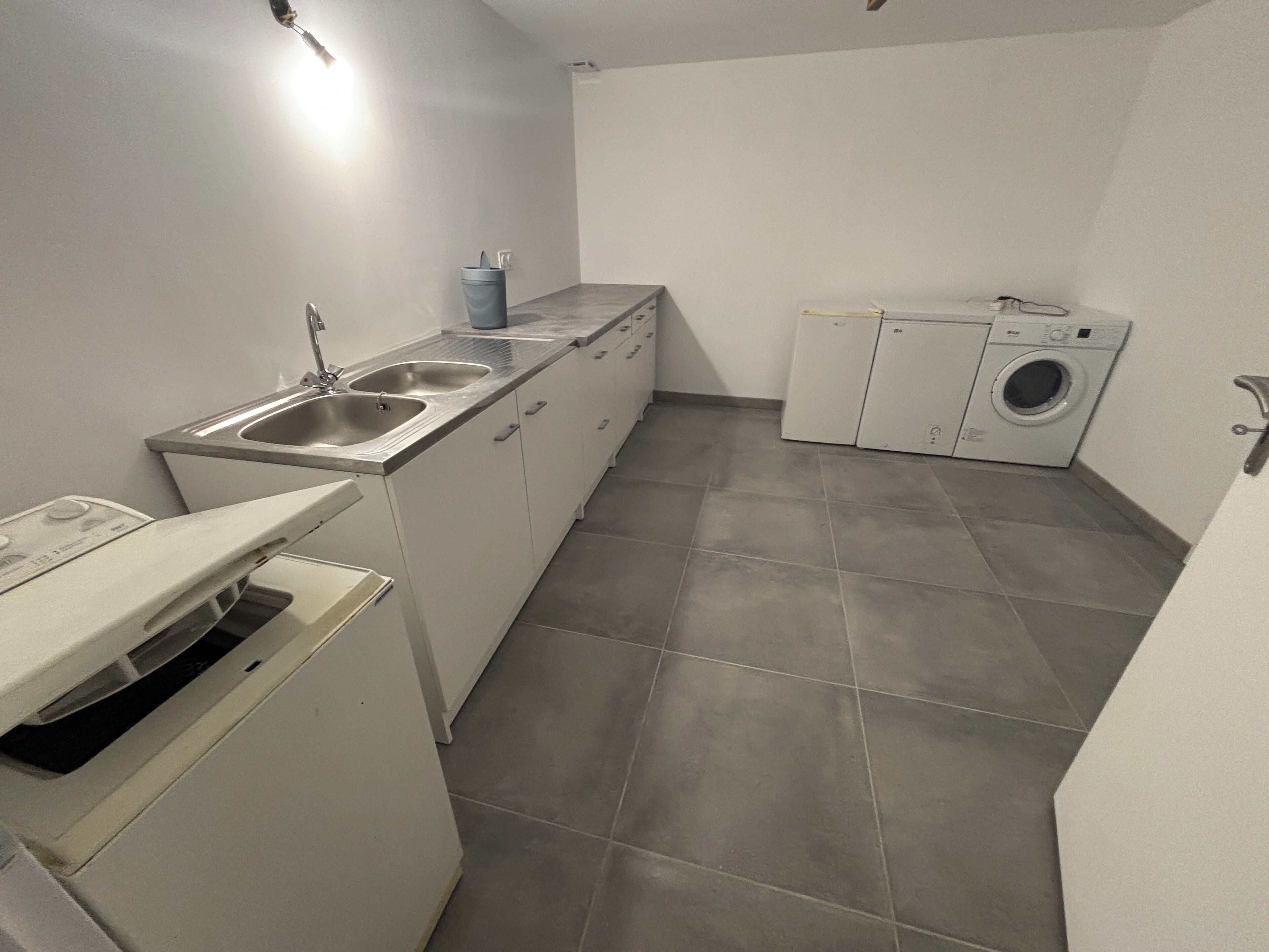 Una cucina compatta con lavello, lavatrice e un piccolo piano di lavoro.