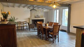Een eetruimte met een houten tafel en stoelen, een open haard en uitzicht op de omgeving.