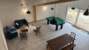A spacious living area with a pool table, a sofa set, and a dining table.