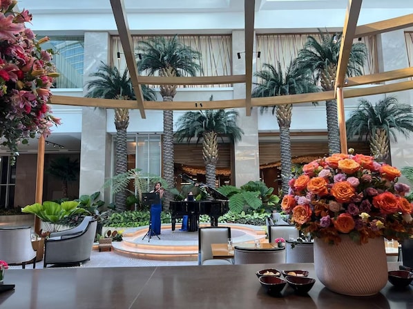 A spacious atrium with a stage, palm trees, and a large floral arrangement. - Luxurious 3BR Ocean-view, Nearby Okada,MOA,Solaire with Free Parking (Parañaque)