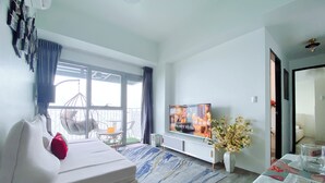 Un salon moderne avec un canapé, un téléviseur et un coin repas où la table est mise.