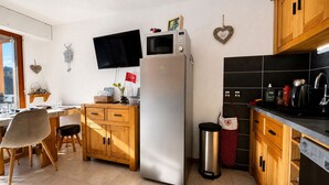 Una cucina con frigorifero, microonde e televisore a parete.