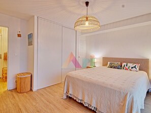 Un dormitorio con una cama grande, una lámpara colgante, un armario y un pequeño cubo de basura.