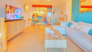 Un salon moderne doté d’un téléviseur à écran plat, de meubles en bois, d’un canapé et d’un coin repas avec des chaises et une table.