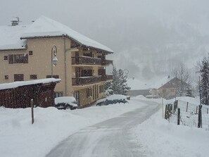 Ein mehrstöckiges Gebäude mit Balkonen, eine verschneite Straße und ein Zaun.