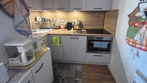 Eine kleine Küche mit weißen Schränken, einer Holzarbeitsplatte, einer Kaffeemaschine, einem Wasserkocher und einem Toaster.