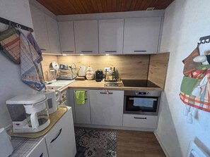 A compact kitchen with white cabinets, a wooden countertop, a coffee maker, a kettle, and a toaster. - 3-Room Apartment in Les Angles with Balcony and Lake View (Les Angles)