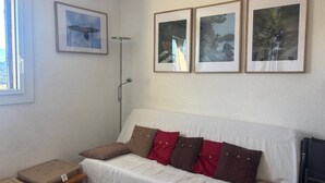 Ein Zimmer mit einem weißen Sofa, braunen und roten Kissen, einem kleinen Holztisch und drei gerahmten Bildern an der Wand.