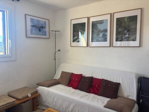 A room with a white sofa, brown and red cushions, a small wooden table, and three framed pictures on the wall. - 3-Room Apartment in Les Angles with Balcony and Lake View (Les Angles)