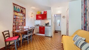 Ett kompakt bostadsutrymme med matplats, kök och en soffa.