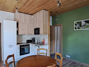 Une cuisine compacte avec des meubles en bois, un four à micro-ondes et une cuisinière. On y trouve également une table à manger avec des chaises.
