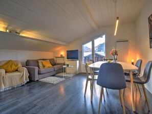Ett modernt vardagsrum med en soffa, en tv och en matplats med stolar och ett bord.