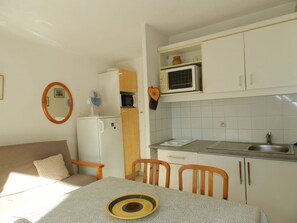 A compact kitchen with a microwave, a small refrigerator, and a sink. There is a dining table with chairs and a small round table with a bowl. - Apartment with pool, sleeps 5, parking, Le Lavandou (Le Lavandou)