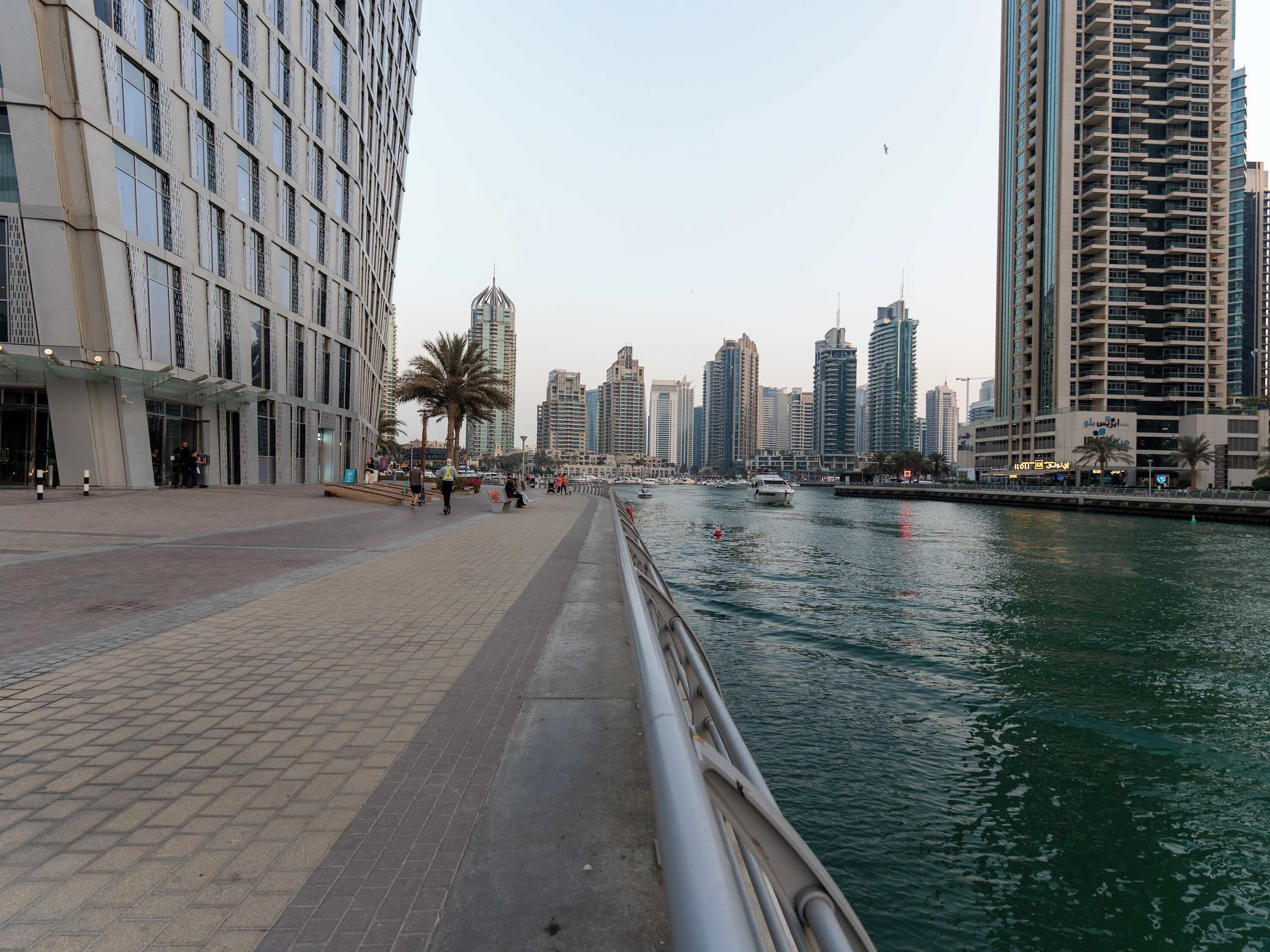 Eine Uferpromenade mit modernen Hochhäusern, einem ruhigen Fluss und einem Fußweg.