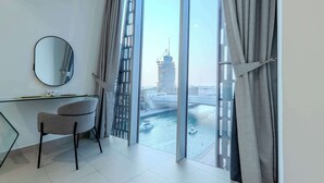 Una habitación moderna con escritorio, silla y ventanas amplias con vistas a un paisaje urbano.