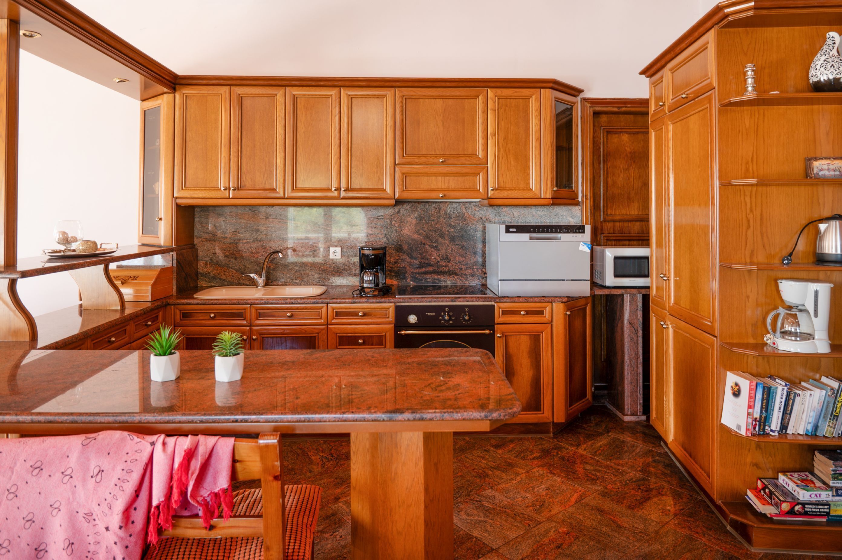 A kitchen with wooden cabinets, a granite countertop, a coffee maker, and a dishwasher.