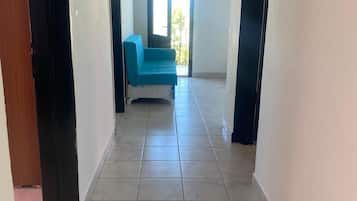 Un couloir avec un canapé bleu, une porte et une fenêtre donnant sur un paysage.