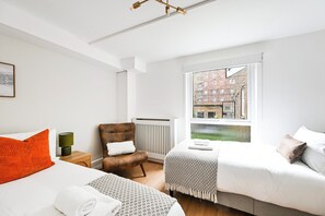 Una camera d'albergo moderna con una grande finestra, un letto, una sedia e un termosifone.