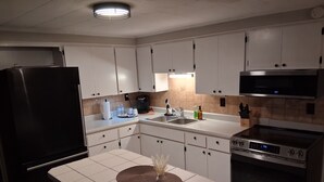 A modern kitchen with white cabinets, a black refrigerator, a stainless steel stove, and a microwave. - Nostalgic 2bed home in Crystal River, Minutes to Kings bay, Manatees &more (Crystal River)