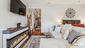 Un salon avec une cheminée, un canapé, un téléviseur fixé au mur et un élément décoratif mural.