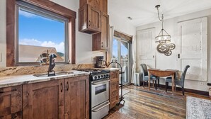 Une cuisine avec des meubles de rangement en bois, une cuisinière et un coin repas comprenant une table et des chaises.