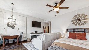 Une chambre à coucher comprenant un lit, un canapé, un bureau et un ventilateur de plafond.