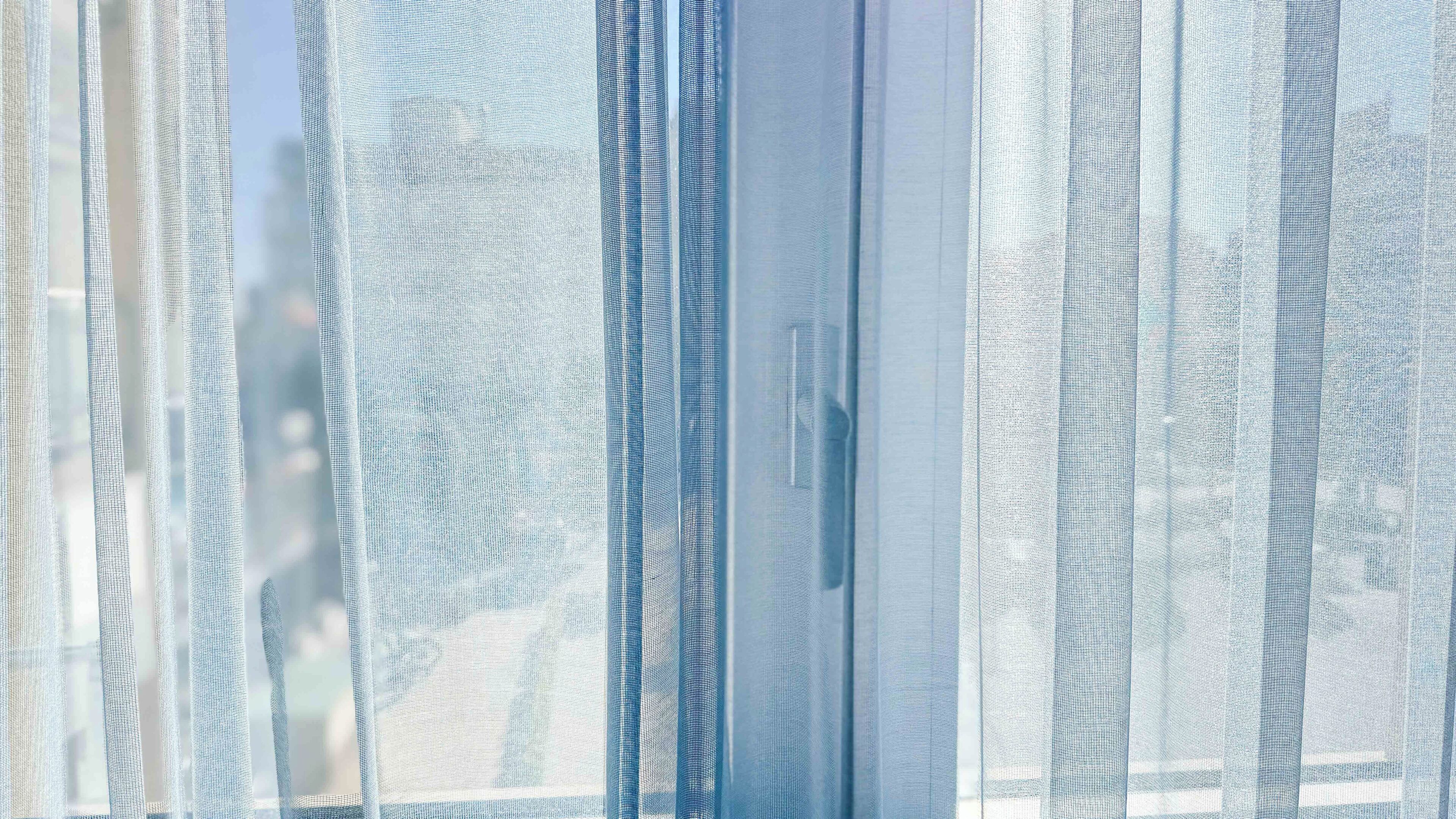 A close-up of sheer, textured curtains with a subtle pattern.