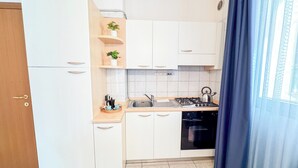 Een moderne keuken met witte kasten, een gasfornuis en een spoelbak.