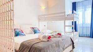 Een hotelkamer met een stapelbed, een bed met een grijze deken, en een wit hoofdeinde.