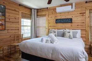 Une pièce aménagée comme un chalet en bois, avec un lit, une chaise, une fenêtre et un panneau décoratif sur le mur.