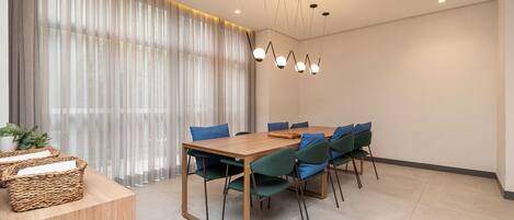 A modern dining area with a wooden table, green chairs, and a chandelier.