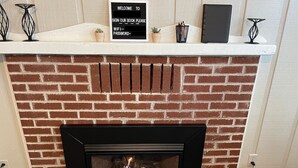 Una chimenea con un cartel arriba, una planta en maceta y un libro en el repisa.