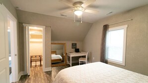 Quarto com cama, escrivaninha e ventilador de teto.