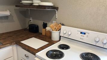 A kitchen with a white stove, wooden countertop, and a white cutting board.