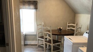Cozinha compacta com mesa de jantar, quatro cadeiras, máquina de lavar e janela com vista.