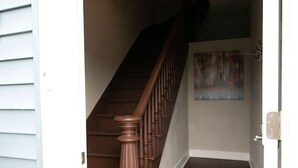 Um corredor com escadas de madeira que levam a um patamar.