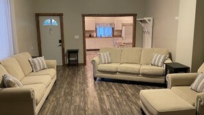A living room with a beige sofa set, a small table, and a wooden floor.
