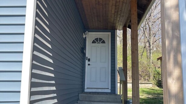 A house with a wooden porch, a white door, and a mailbox.