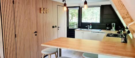 A modern kitchen with a wooden island, bar stools, and pendant lighting.
