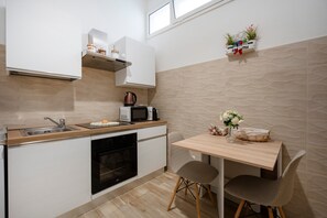 A compact kitchen with a microwave, kettle, and a small dining area with two chairs and a table.