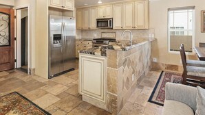 Una cocina con isla central, electrodomésticos de acero inoxidable y armarios color beige.
