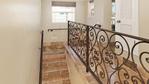 Una escalera con barandilla de metal decorativa y una ventana en la parte superior.