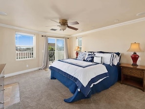 A bedroom with a bed, a ceiling fan, a nightstand with a lamp, and a view of the outside. - Steps to the Sand in South Mission Beach 4BR Ocean Views Sleeps 10 (San Diego)