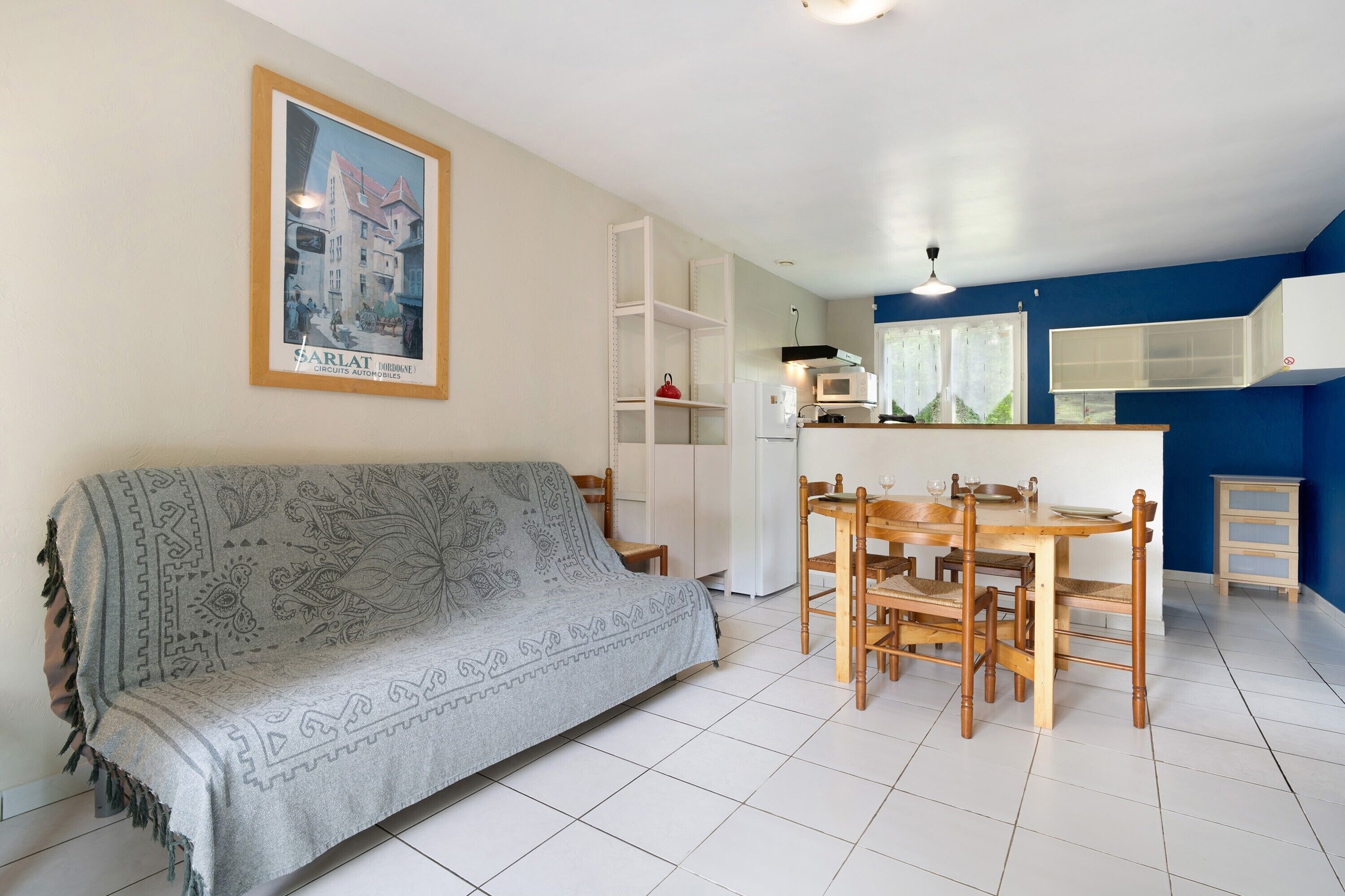 Ein Wohnzimmer mit einer Couch, einem Esstisch, Stühlen und einer Küchenzeile mit einer Mikrowelle.