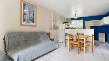 Ein Wohnzimmer mit einer Couch, einem Esstisch, Stühlen und einer Küchenzeile mit einer Mikrowelle.