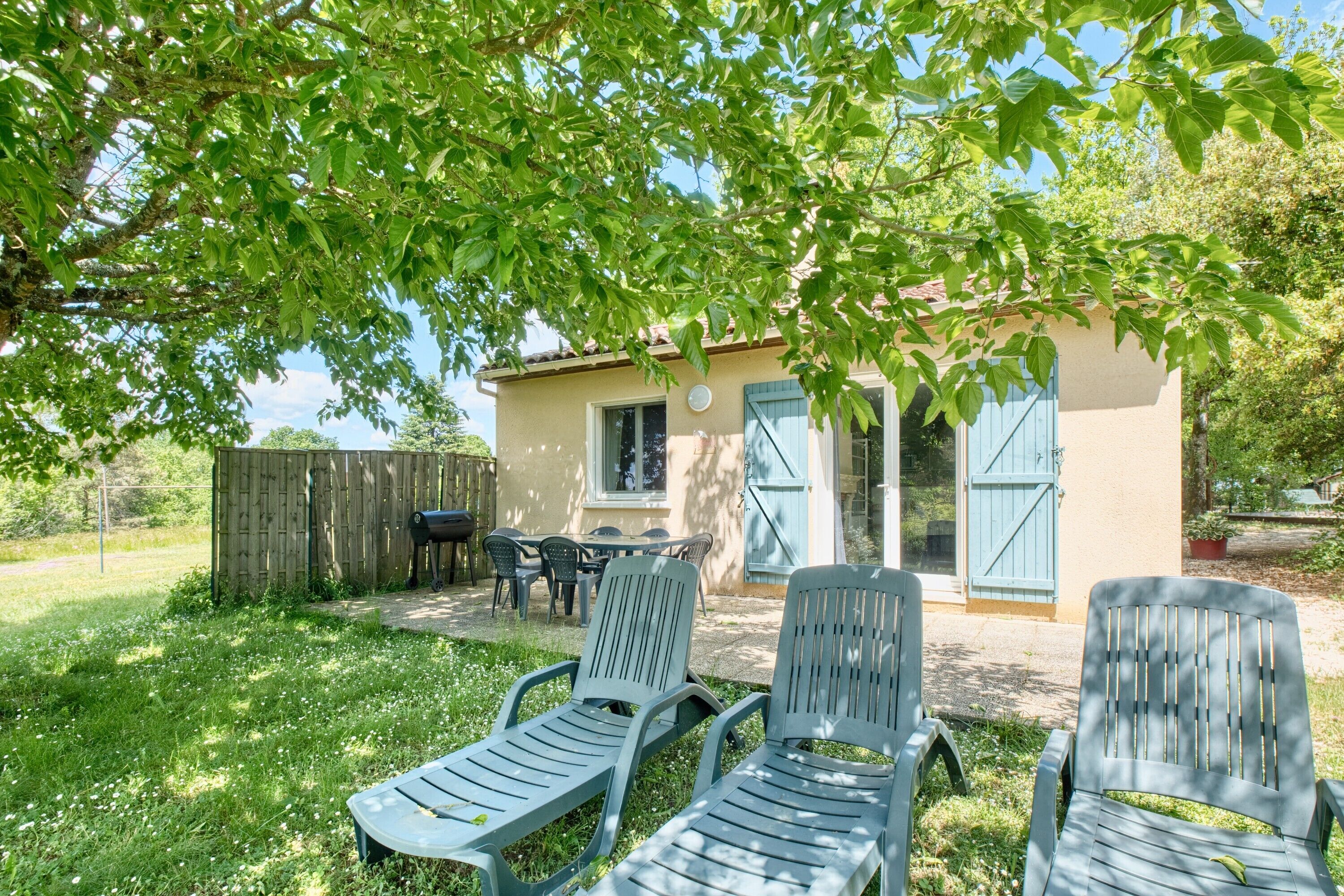 Ein Haus mit Terrasse, Sitzgelegenheiten im Freien und einem Zaun.