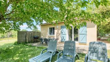 Ein Haus mit Terrasse, Sitzgelegenheiten im Freien und einem Zaun.