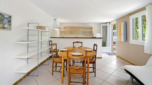 A dining area with a round table, chairs, and a white shelf unit.