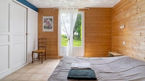A bedroom with a bed, a chair, a door, and a window with curtains.
