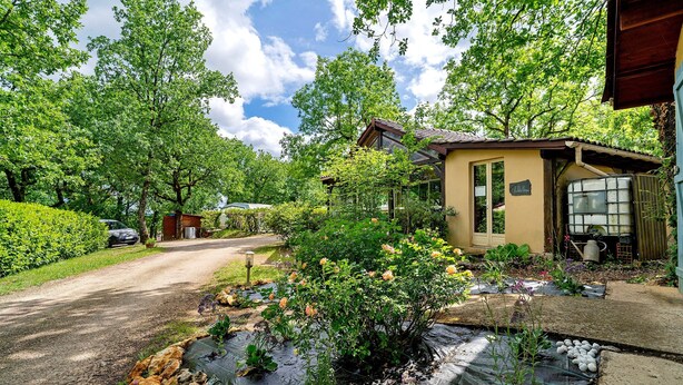 A house with a garden, a driveway, and a car parked on the side.